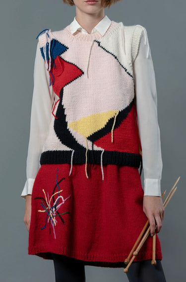 Woman wearing wool vest and red wool skirt. The skirt is knee length and has colourful embroidered lines on the right leg.